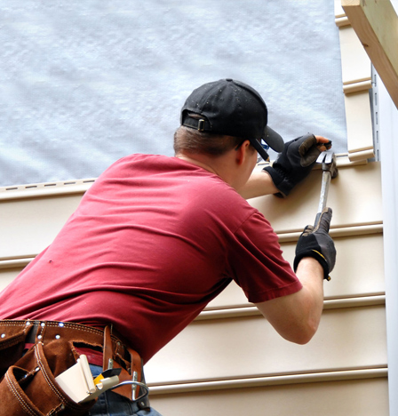 A roofer installing siding on a house