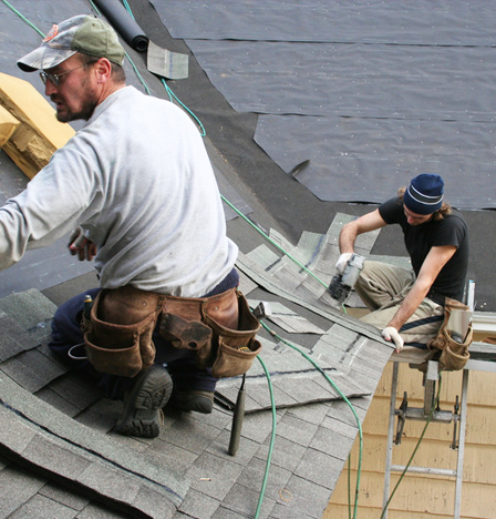 Two roofers removing old roof tiles.